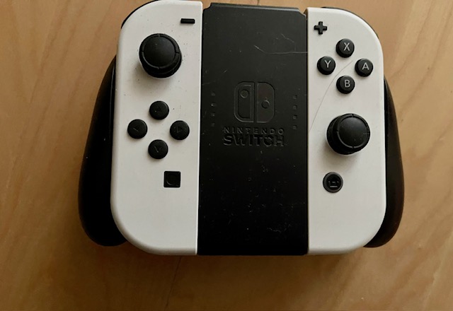 Das Bild zeigt einen weißen Nintendo-Switch-Controller mit dunklen Knöpfen.